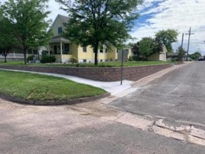 The front yard of a house with stone buttresses separating it from the sidewalk with landscaping by by Total Lawn Care & Landscape in Sterling, CO