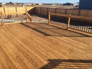 A large wooden patio leading to a stone path designed and placed by Total Lawn Care & Landscape in Sterling, CO